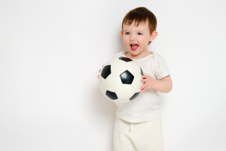 Happy baby holding a soccer ball on a studio white background. Smiling child playing football. Kid about two years old (one year nine months)の写真素材