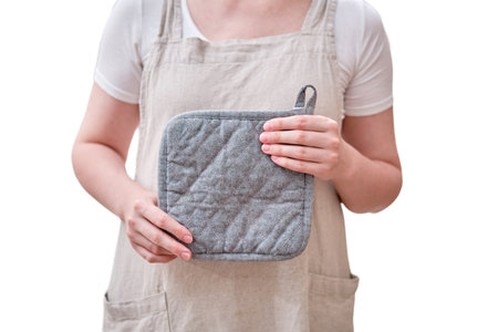 A potholder in the hands of a woman in the kitchen, isolated on a white background. Female hands holding a kitchen towelの写真素材