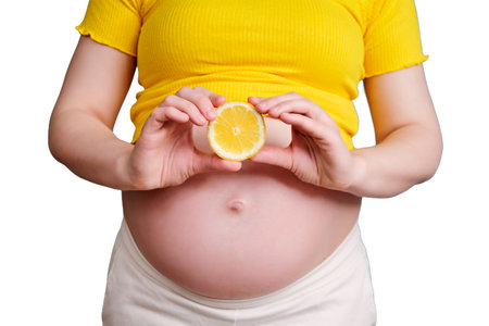 Half a lemon in the hands of a pregnant woman, isolated on a white backgroundの写真素材