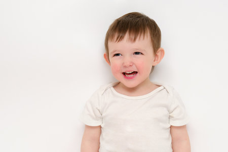 A happy baby on a studio white background. Portrait of a smiling child. Kid aged about two years (one year nine months)の写真素材