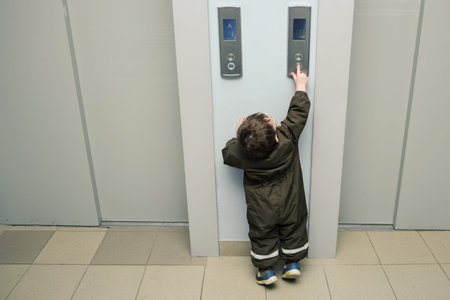 A small child presses the elevator call button. Baby reaches for the elevator button in a...