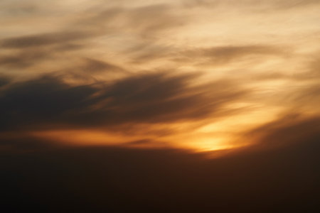 Sunset sky with red light of the setting sun. Evening clouds in the orange light of sunset raysの写真素材