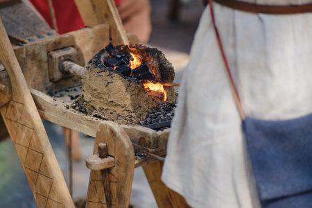 A blacksmith in a forge forges metal. Blacksmithing in retro style outdoorsの写真素材