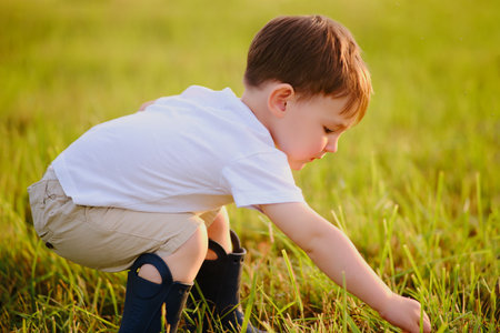 Amidst a picturesque sunset, a curious kid explores the farm, running through the field. Portrait of a happy kid aged two yearsの写真素材