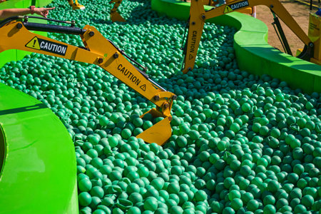 Training to work on a toy excavator, practice for children when choosing a profession. Green plastic balls on a children's playgroundの写真素材