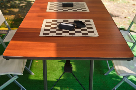 Wooden table with chess pieces on it and chairs in the gardenの写真素材