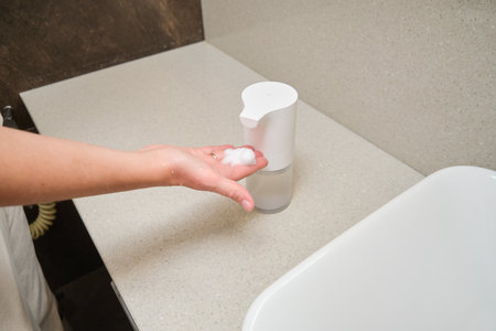 Hand of a woman holding a soap dispenser with a white foam, Xiaomi - Moscow, Russia, September 19, 2023のeditorial素材