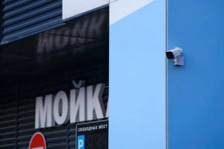 A surveillance camera at the corner of the facade of a blue building with a car wash. Translation...