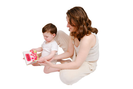 Happy baby with mother reading a book on studio, isolated on white background. Portrait of a smiling child with mom, isolated on white background. Kid about two years old (one year nine months)の写真素材