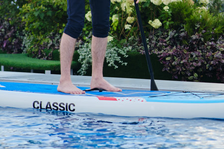 Man stand up paddle board in the swimming pool. close-up of legsの写真素材