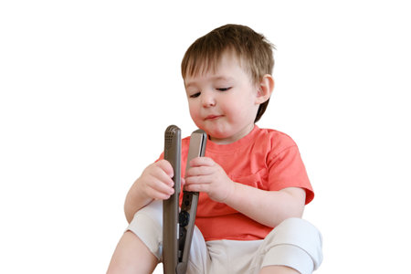 The baby innocently explores with curling devices, putting themselves at risk of getting burnt or injured, isolated on white background. Kid about two years (one year ten months aged)の写真素材