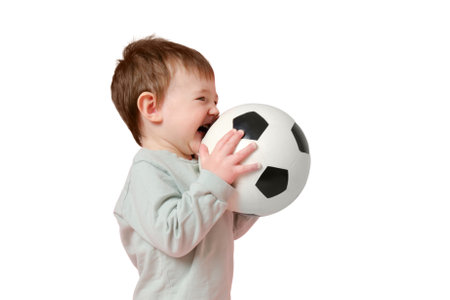 Happy toddler baby with a soccer ball on a studio, isolated on white background. Child boy holding a sports ball in his hands, isolated on white background. Kid age one year eight monthsの写真素材