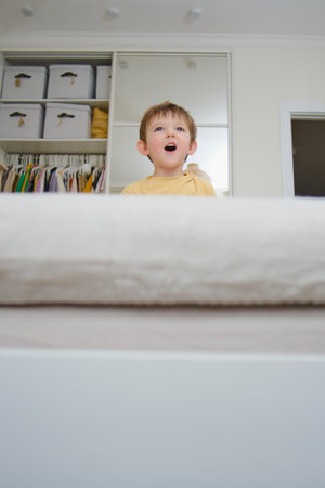 The baby is playing alone on the bed and might fall down if not taken care of. Kid aged two years (two-year-old boy)の写真素材
