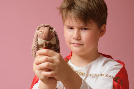 Child with a toy in his hands on a pink background.の写真素材