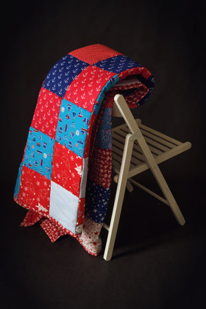 Handmade blanket on a wooden chair with a red and blue pattern