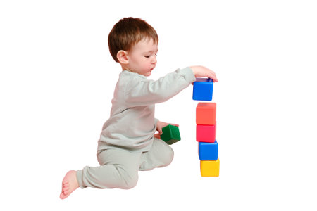 Happy toddler baby plays with cubes on studio, isolated on white background. Child boy builds a tower of toys, isolated on white background. Kid age one year eight months, full heightの写真素材