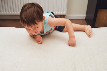Baby is climbing on the edge of the bed, there's a risk of an indoor accident. Kid aged two years (two-year-old boy)の写真素材
