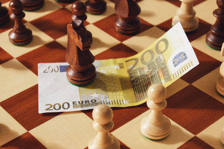 Money in euros with chess pieces of kings on the chessboard, close-up.の写真素材