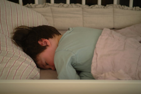 Baby boy sleeps in a crib and tosses, kid age two years and five months. The child is sleeping in bedの写真素材