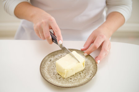 Close-up of a woman's hands cutting butter on a plate. Process of cooking pecan pie in home kitchen...
