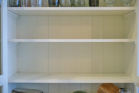 Empty shelves of the kitchen cabinet without dishes and platesの写真素材