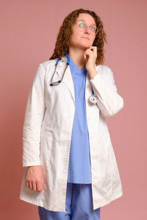 Pensive woman doctor, studio pink background. Nurse in uniform with stethoscope on red studio backgroundの写真素材