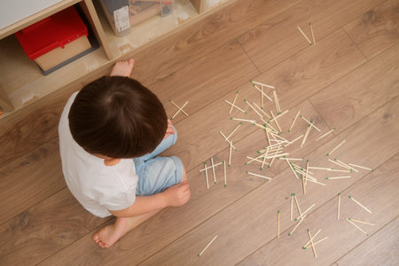The child is carelessly lighting matches indoors, which could lead to burns. A baby playing with flammable objects like matches is a serious fire hazard. Kid aged 3 years (three year old boy)の写真素材