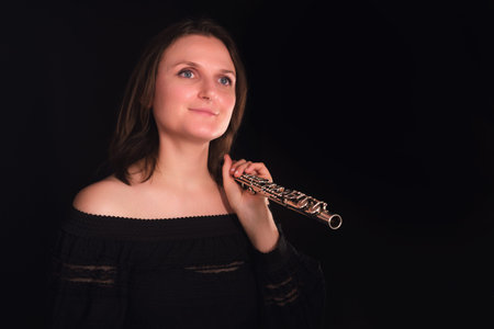 Portrait of a female flutist with a silver instrument. Classical music and artistry concept.