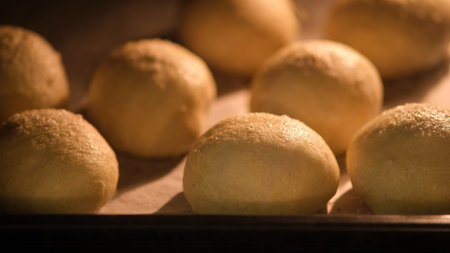 Dough balls baking in oven on parchment paper. Close-up photography with warm lighting. Homemade...