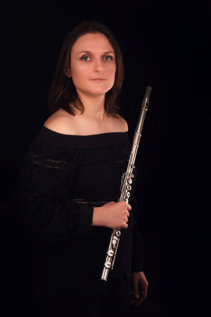 Elegant woman posing with flute in studio. Orchestral music and performance theme.の写真素材