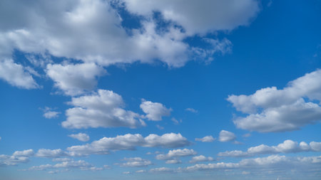 Blue sky with scattered white clouds. Natural background with copy space. Weather and atmosphere concept for design and printの写真素材