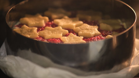 Raw raspberry pie with star-shaped shortcrust pastry on top baking in metal cake ring. Studio food photography. Holiday dessert preparation. Christmas baking concept for design and printの写真素材