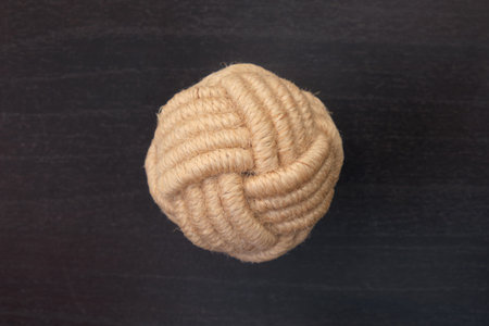 Drawer pull handle wrapped in natural beige rope on dark wooden surface. Studio object photo. Design...