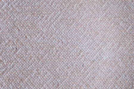Close-up of beige woven textile texture. Macro shot of coarse fabric pattern with visible interlaced...