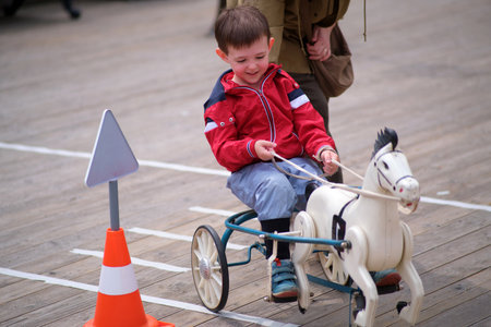 A boy plays with a ride on toy horse, smiling as he steers the wheeled toy. Childhood fun and play concept. A child aged 3 yearsの写真素材