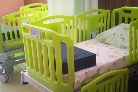 Hospital cot or bed with green side rails. Empty baby bed in a medical clinic ward. Child healthcare and recovery concept.の写真素材
