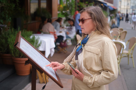 Woman looks at restaurant menu outside. Visitor reads menu on street. Modern dining experience....