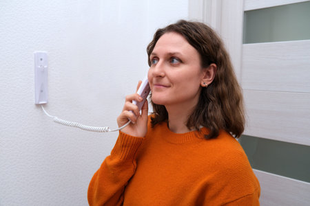 Happy woman answers intercom device. Modern apartment security system concept. Home communication...