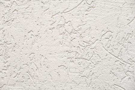 White stucco wall texture background with rough granular pattern. Detailed abstract surface for interior design, building material, or decorative plaster concept.の写真素材