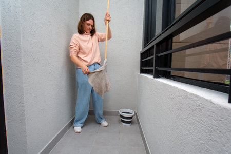 Woman at home with mop for floor cleaning. Regular chore performing concept. Everyday house cleaning ritual for cleanliness.の写真素材