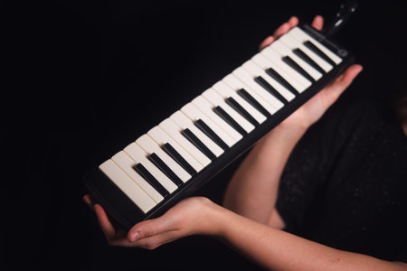 Woman holding a melodica, a musical instrument with piano-style keys, representing music education and creative hobbies.の写真素材