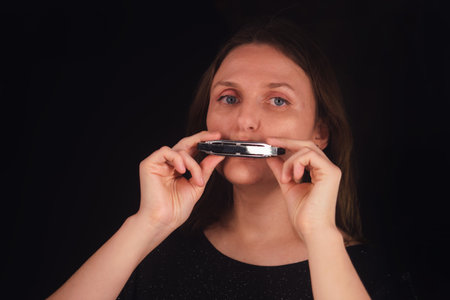 Woman playing blues harmonica. Musician performing music. Concept of melodic sound and musical passion for advertising and concert poster.の写真素材