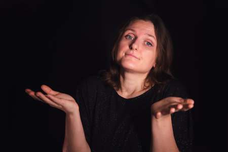 Woman shrugging her shoulders with open hand gesture indicating uncertainty and confusion. Expressing doubt, indifference, or lack of knowledge.の写真素材
