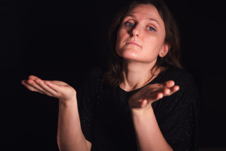Woman shrugging with hands up. Concept of doubt, questioning, and uncertainty. For expressing confusion or lack of knowledge.の写真素材