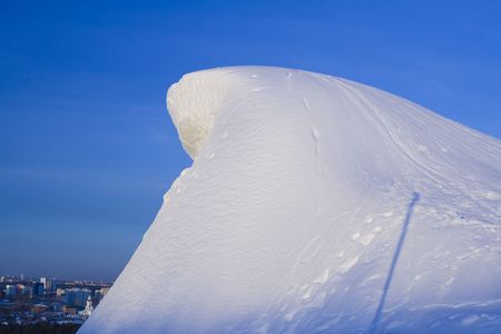 Sunny snowpeak with tracks to its top, big city downhill  and blue sky as a backgroundの写真素材