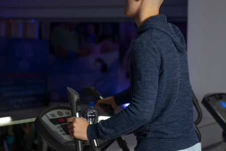 Young healthy boy is working out on a elliptic trainer. Health and sport concept. Healthy lifestyles