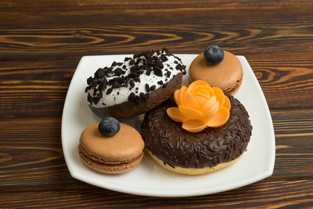 Chocolate donuts with icing and berries lie on a plateの写真素材