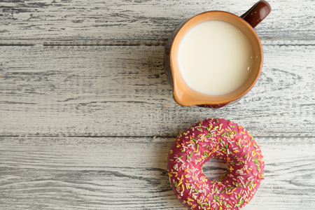 Donut with icing on white wooden background with milk jugの写真素材
