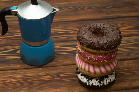 Donut with icing on dark wooden background with a coffee potの写真素材