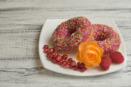 Donuts with icing and berries on the plateの写真素材
